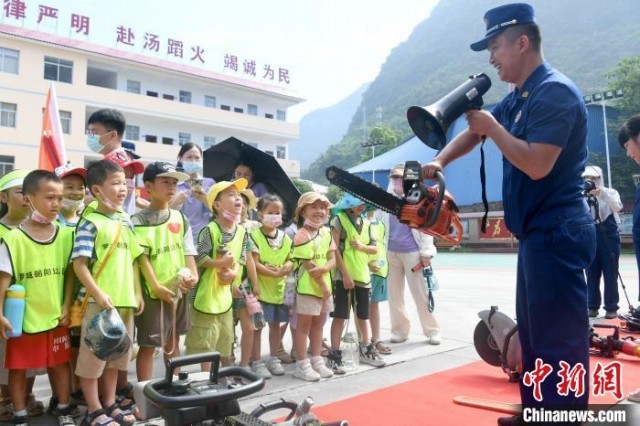 图为消防员在向孩子们介绍消防器材功能和使用方法。　廖光福 摄