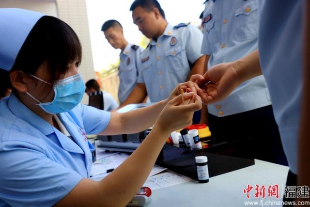 图为消防救援人员配合医护人员进行血液筛查（司寒杰摄）