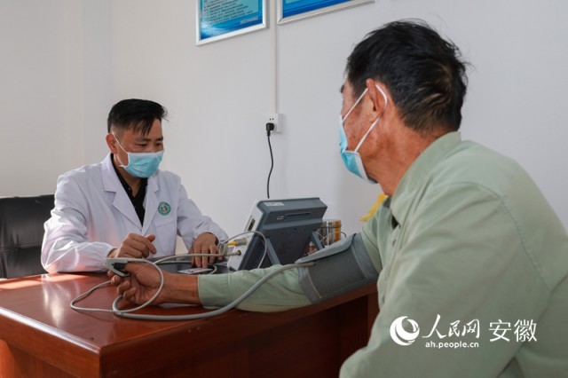 肥西县花岗镇大黄村，医生刘秀波（左）在新投入使用的卫生室里为村民检查身体。人民网 张俊 摄
