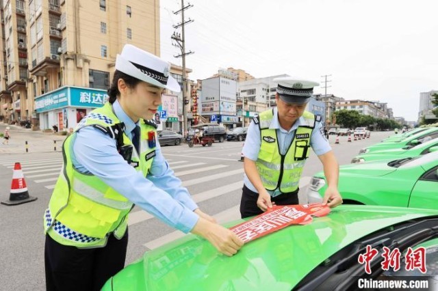 6月6日，在广西柳州市融安县长安广场，交警为参加爱心送考的车辆张贴“爱心送考”标志。　谭凯兴 摄
