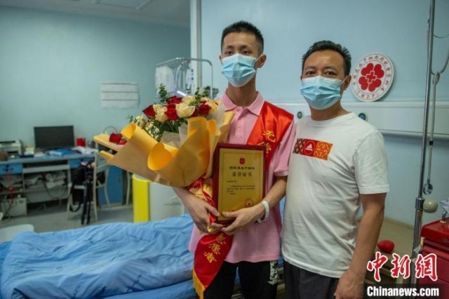 捐献病房里王浩臻(左)手捧鲜花和捐献证书与医生父亲在一起。　刘忠俊 摄